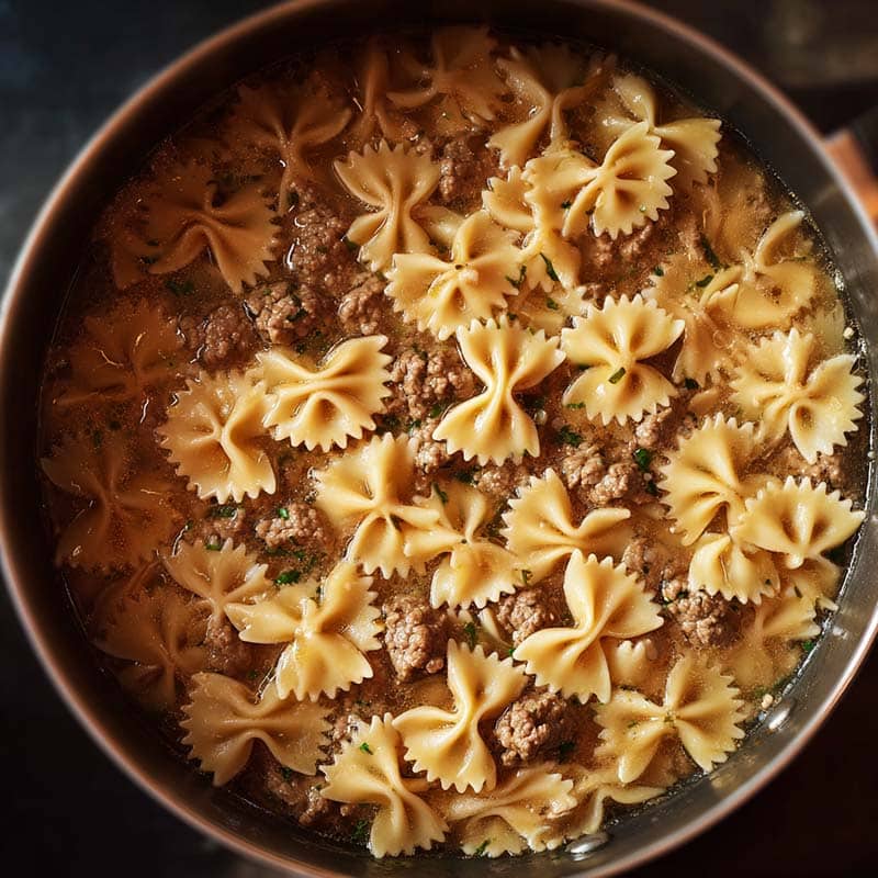 simmering bowtie pasta in broth