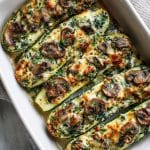 Spinach mushroom and ricotta stuffed zucchini boats in a ceramic baking dish