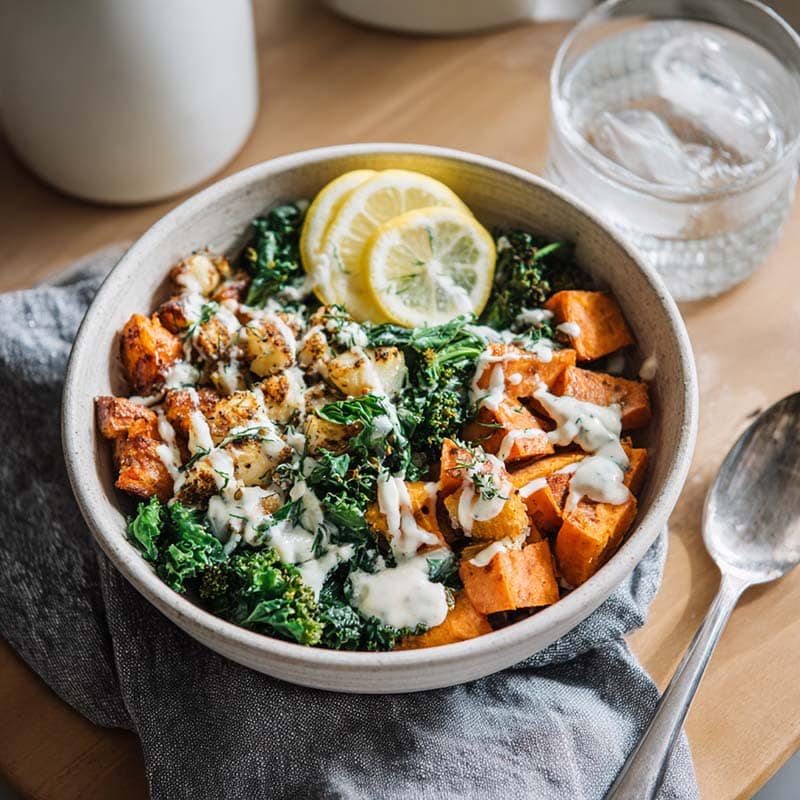 Served sweet potato Mediterranean breakfast bowl with tahini drizzle and lemon water